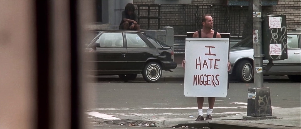 Bruce Willis tenant un signe "I hate niggers" dans le quartier new-yorkais de Harlem.
